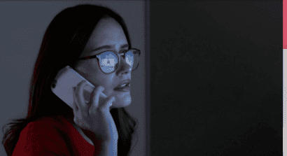 Person on phone looking at fraud notification on computer
