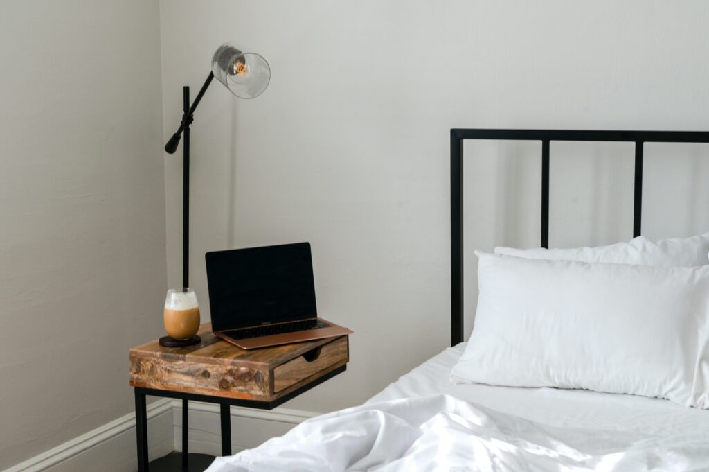 Bed in a shortterm rental property with a laptop and coffee on the bedside table