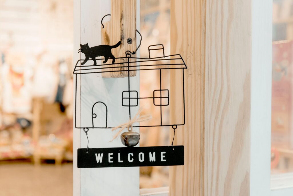 The 'welcome' text sign with the drawing of the short-term rental unit and cat is laid over the interior of the Airbnb where a guest will stay