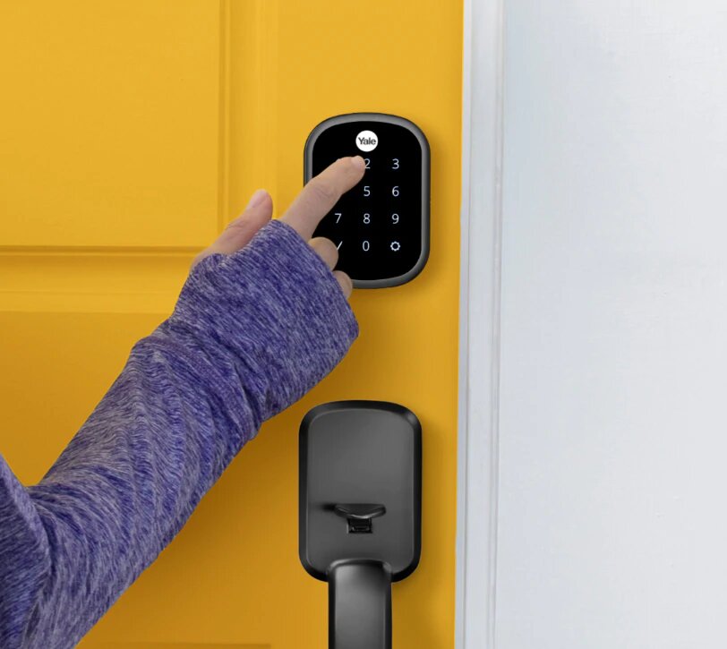 A photo of a woman using a Yale keypad to open a door