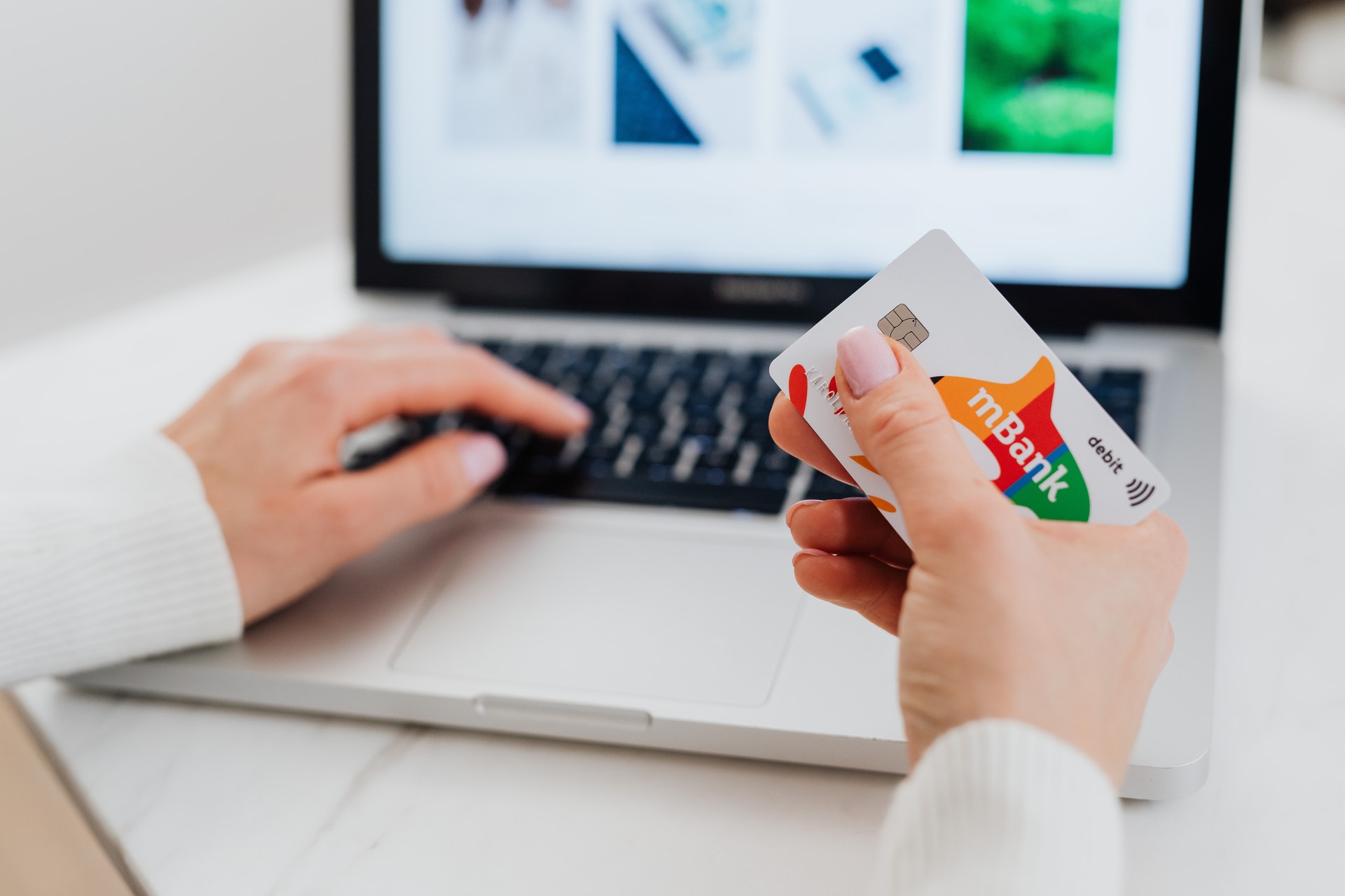 A woman holding a debit card while using her laptop
