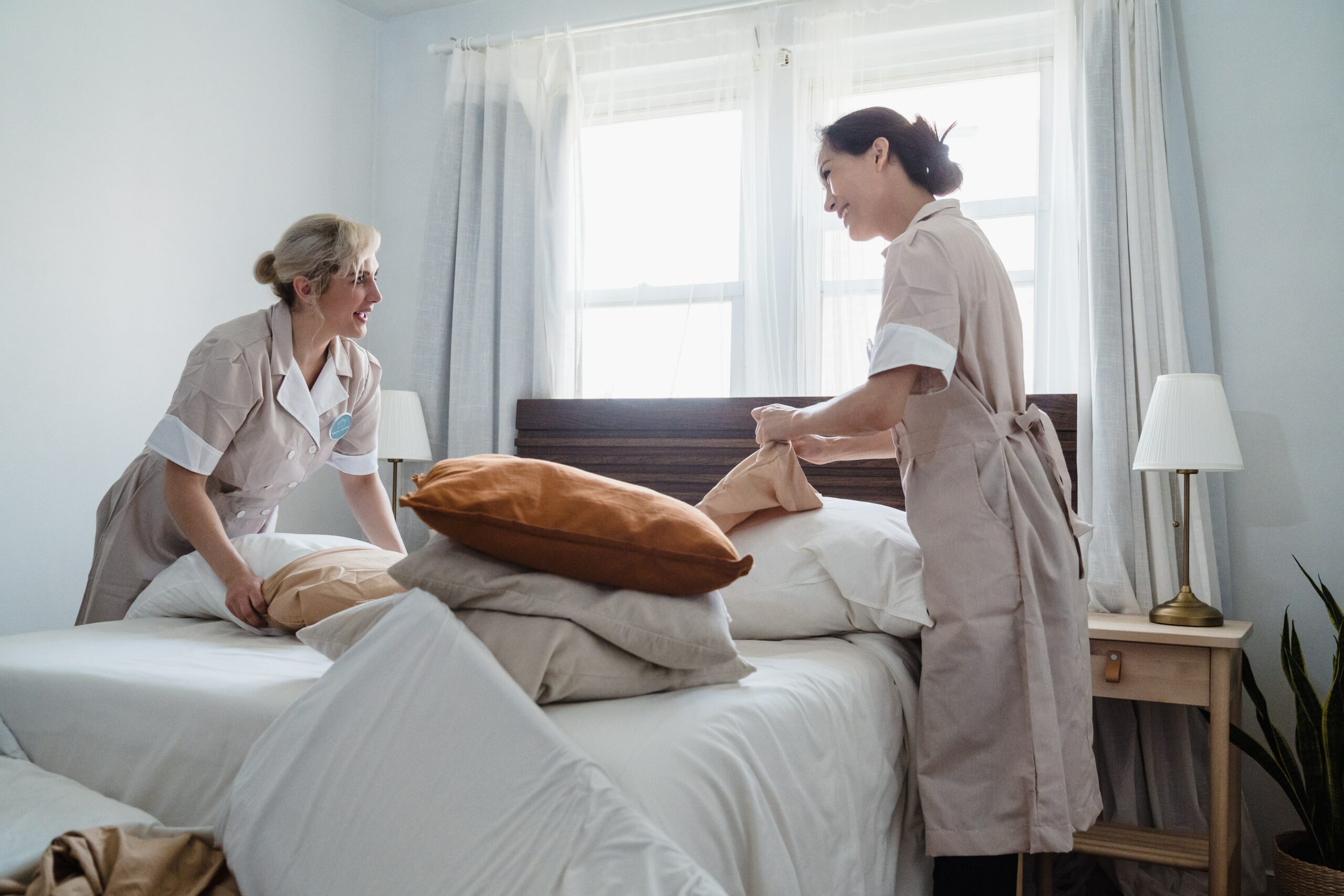 Image of two women making a bed in a vacation rental