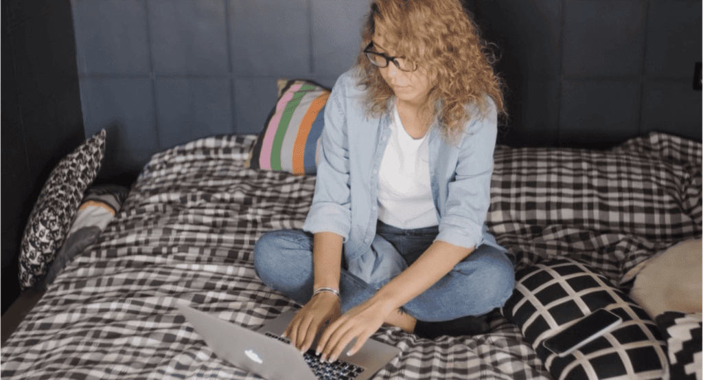 Person working on their laptop on top of a bed