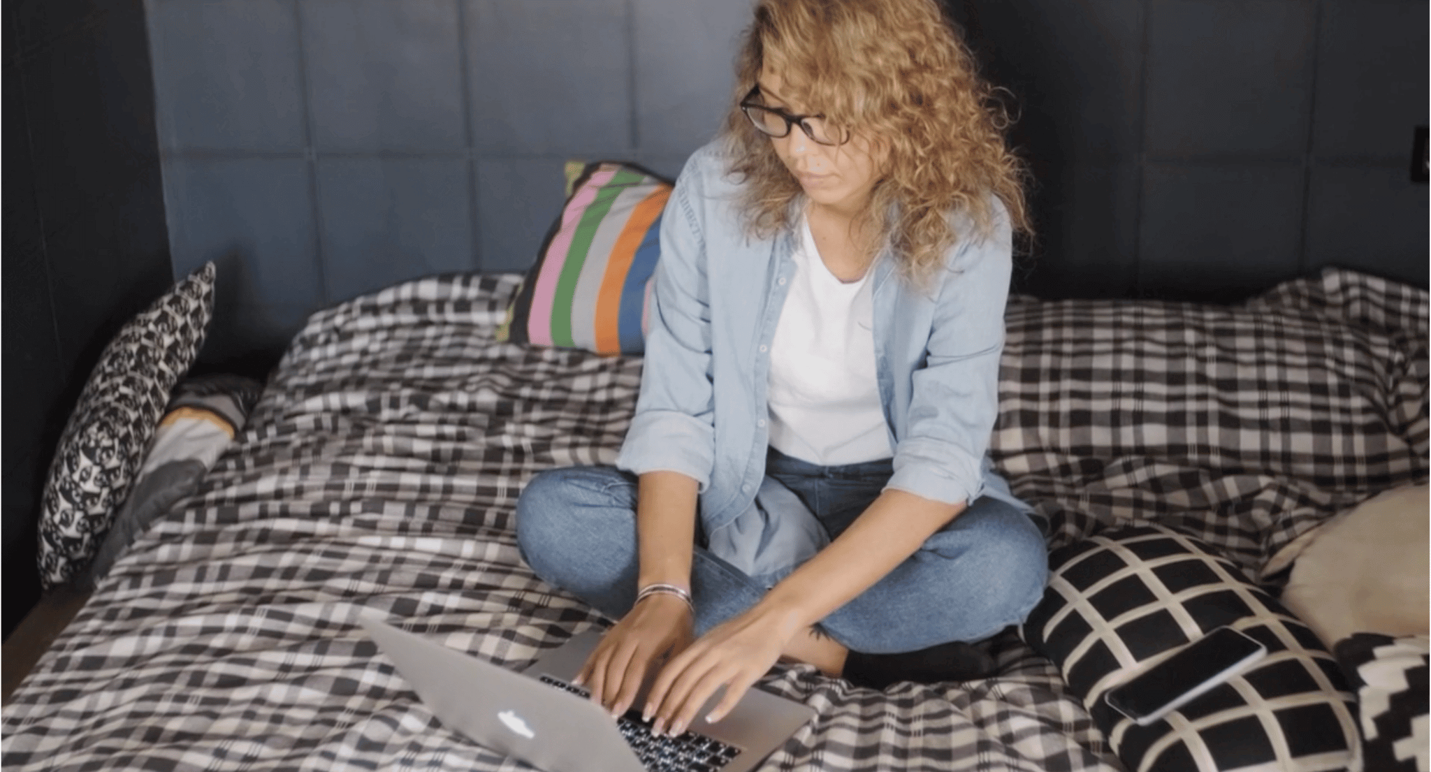 Person working on their laptop on top of a bed