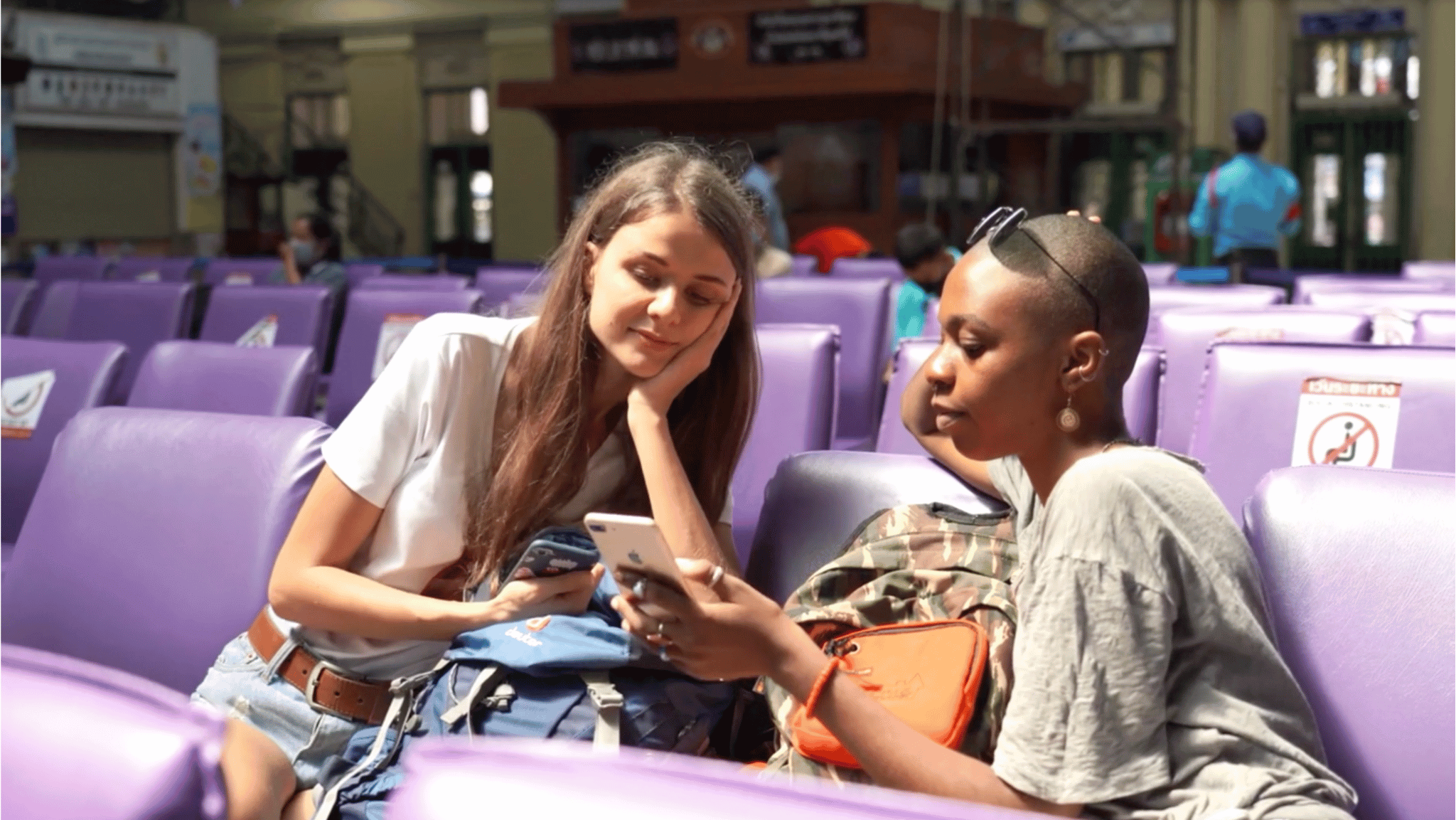Two travellers looking at a phone in a train station
