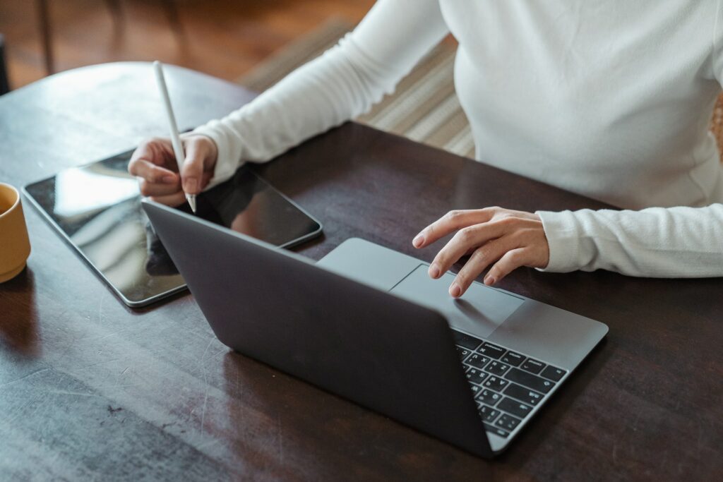 A photo of a woman using a laptop and tablet to show the perfect tech stack
