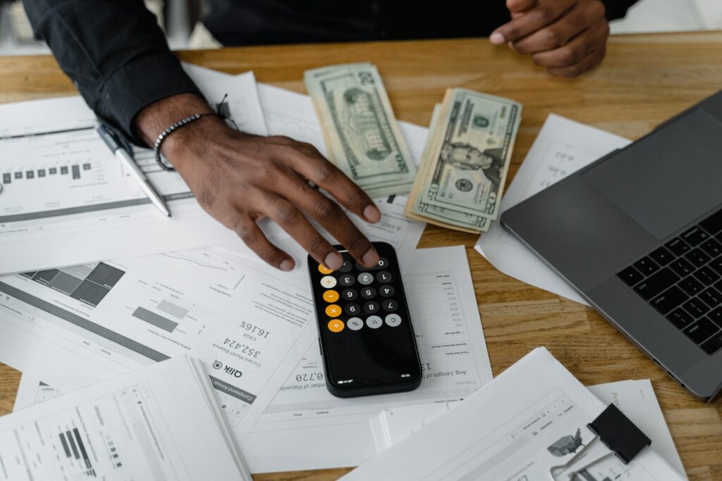 A photo of a man using a calculator with money on the table