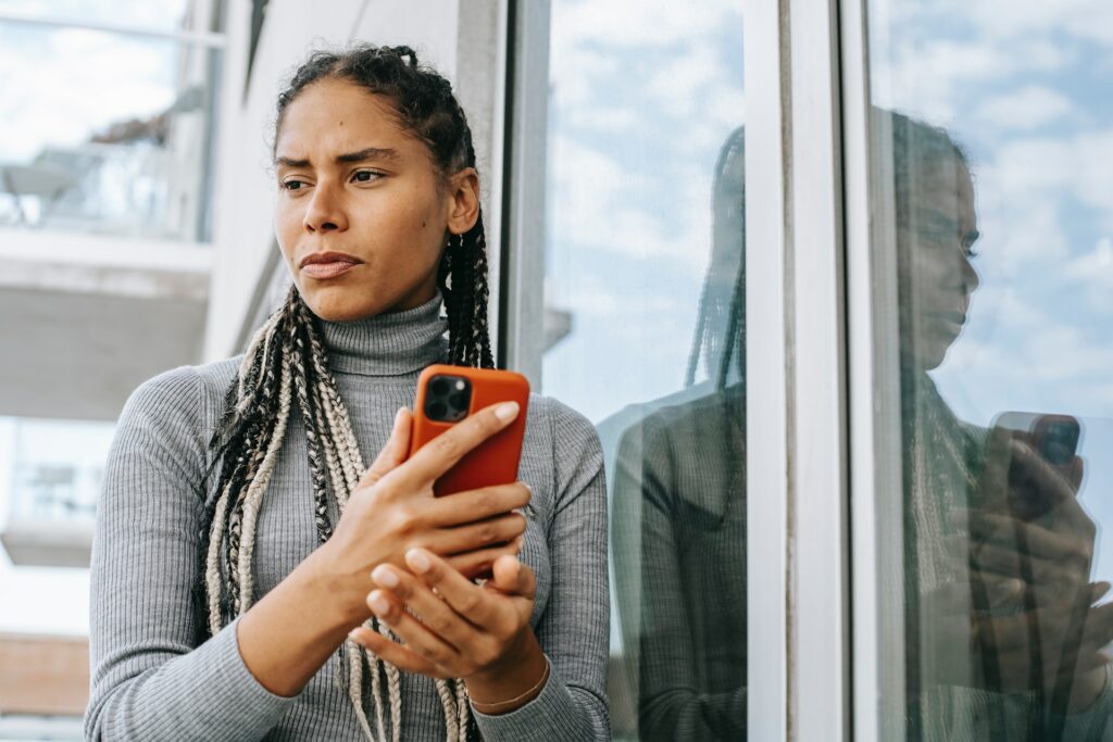 A photo of a woman holding a phone looking worried