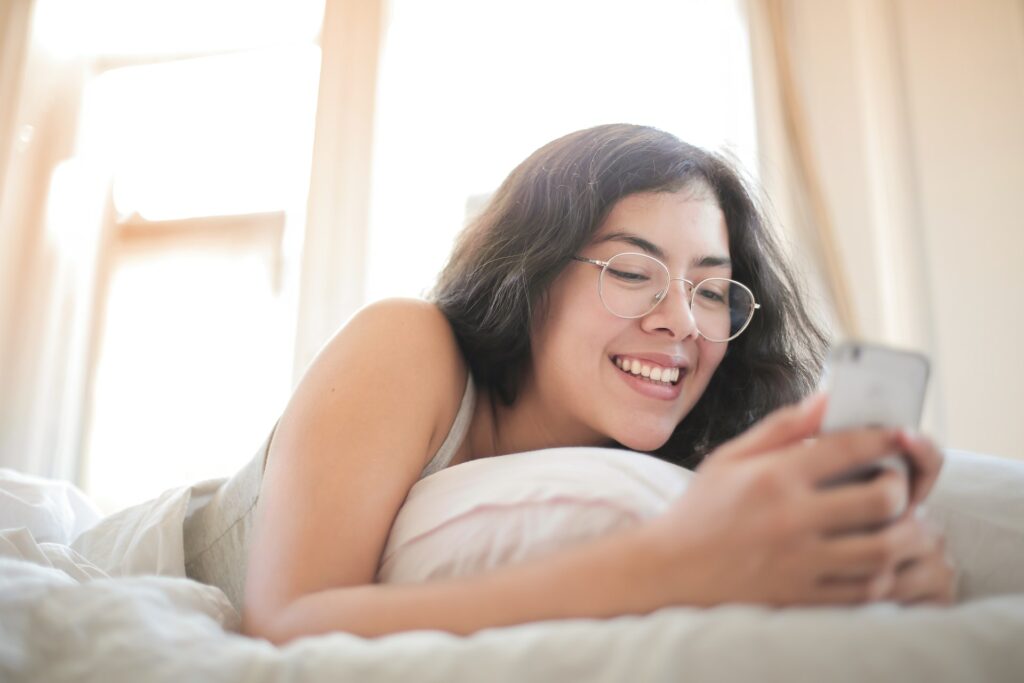 A photo of a woman smiling at her phone to show good conversation