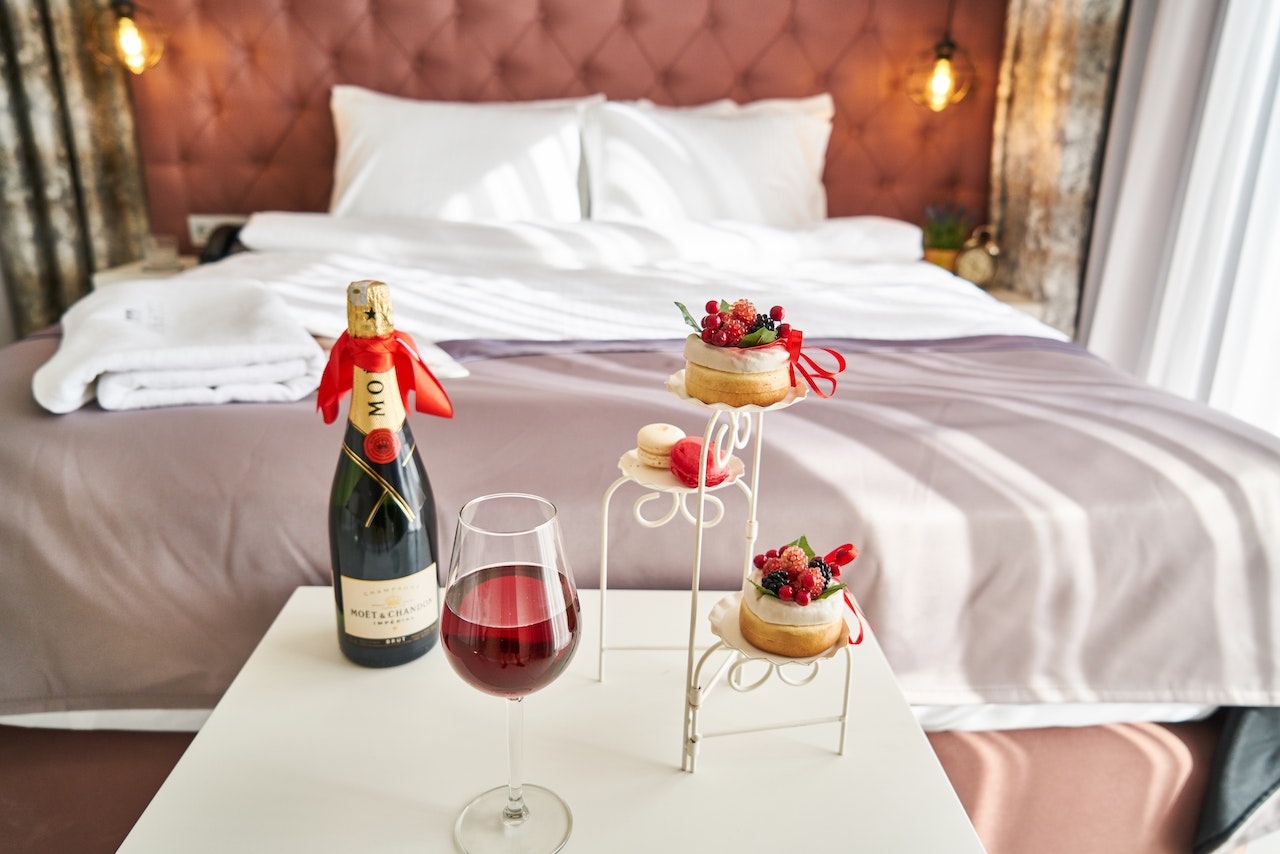 Image of a hotel room with wine and a tray of desserts 